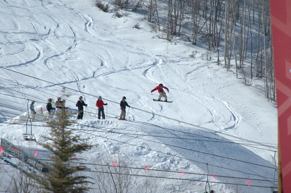 Snowboarder catching some air with onlookers
